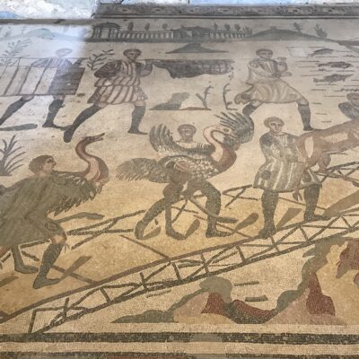 Ostriches and an antelope are brought up a gangway to a ship bound for Italy. From Piazza Armerina.